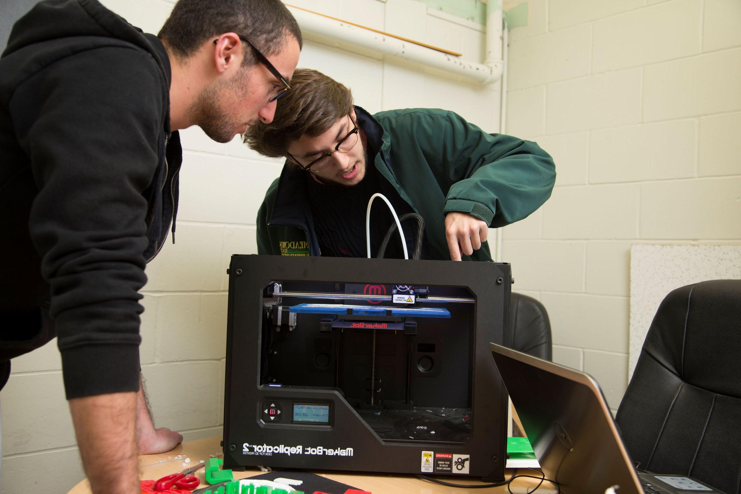 Two engineering students working on a replicator machine.